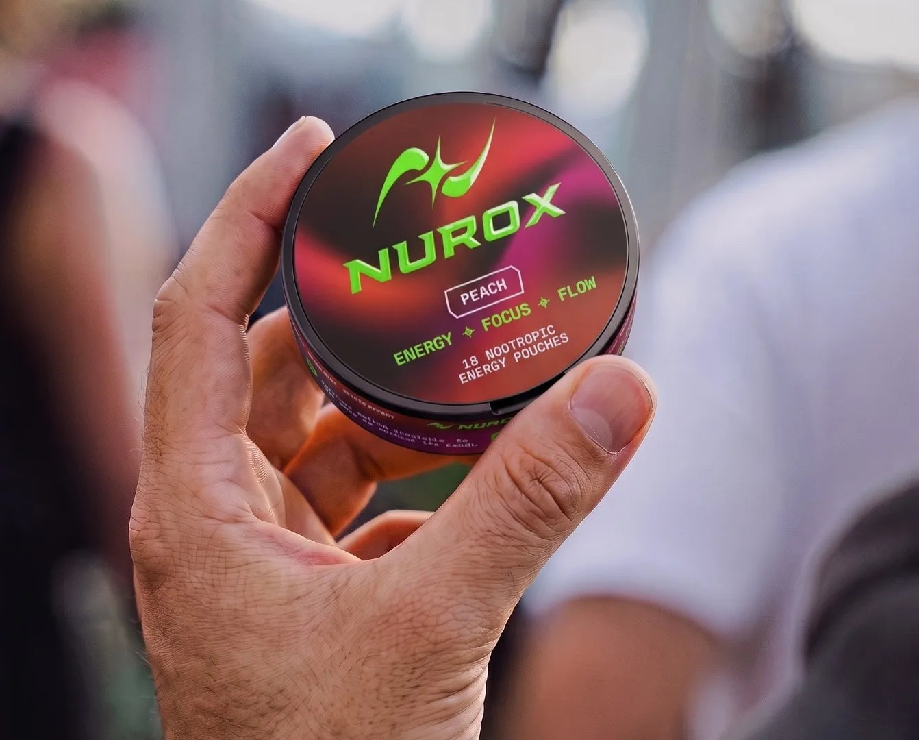 Hand holding a Nurox Peach tin