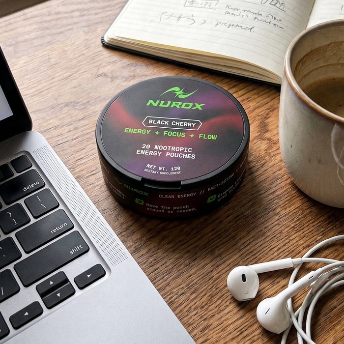 NUROX tin on a desk beside a laptop, notebook and coffee